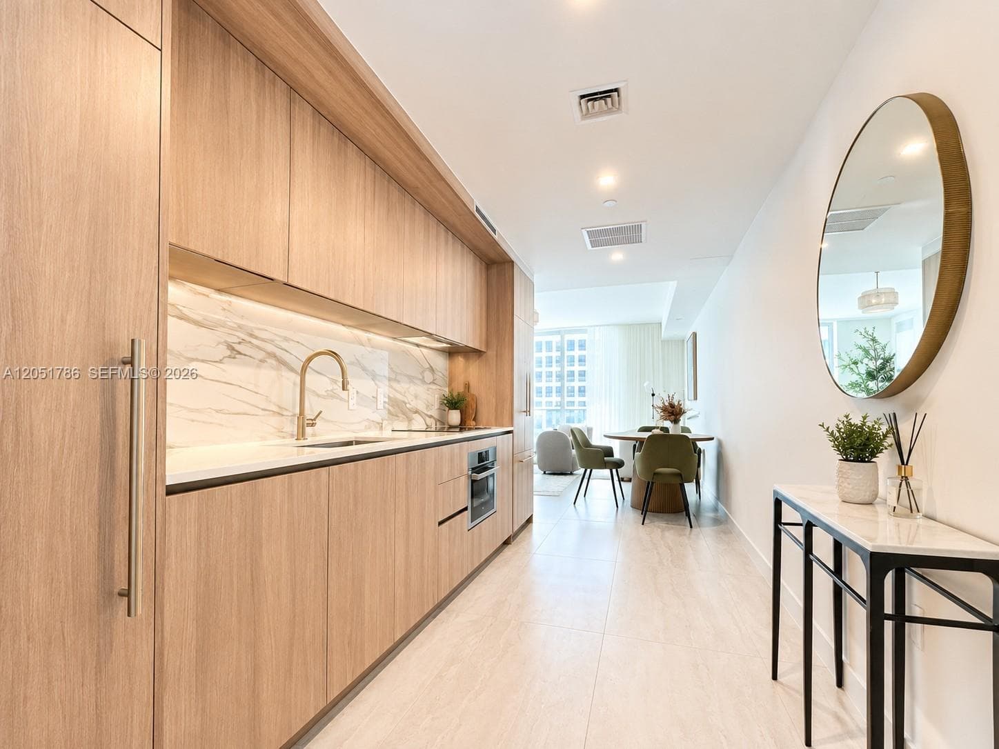 Custom flat-panel wood-finish cabinetry, integrated appliances, stone-surface backsplash, recessed lighting, and large-format tile flooring