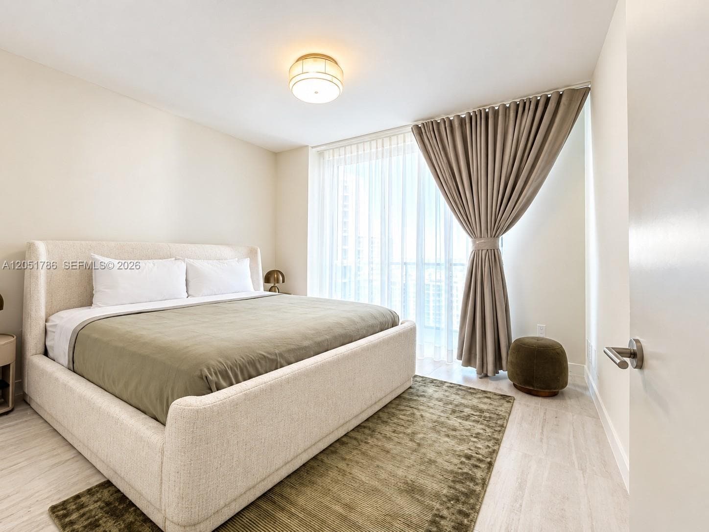 Floor-to-ceiling windows with floor-length drapery, wood-finish flooring, and a circular flush-mount ceiling light