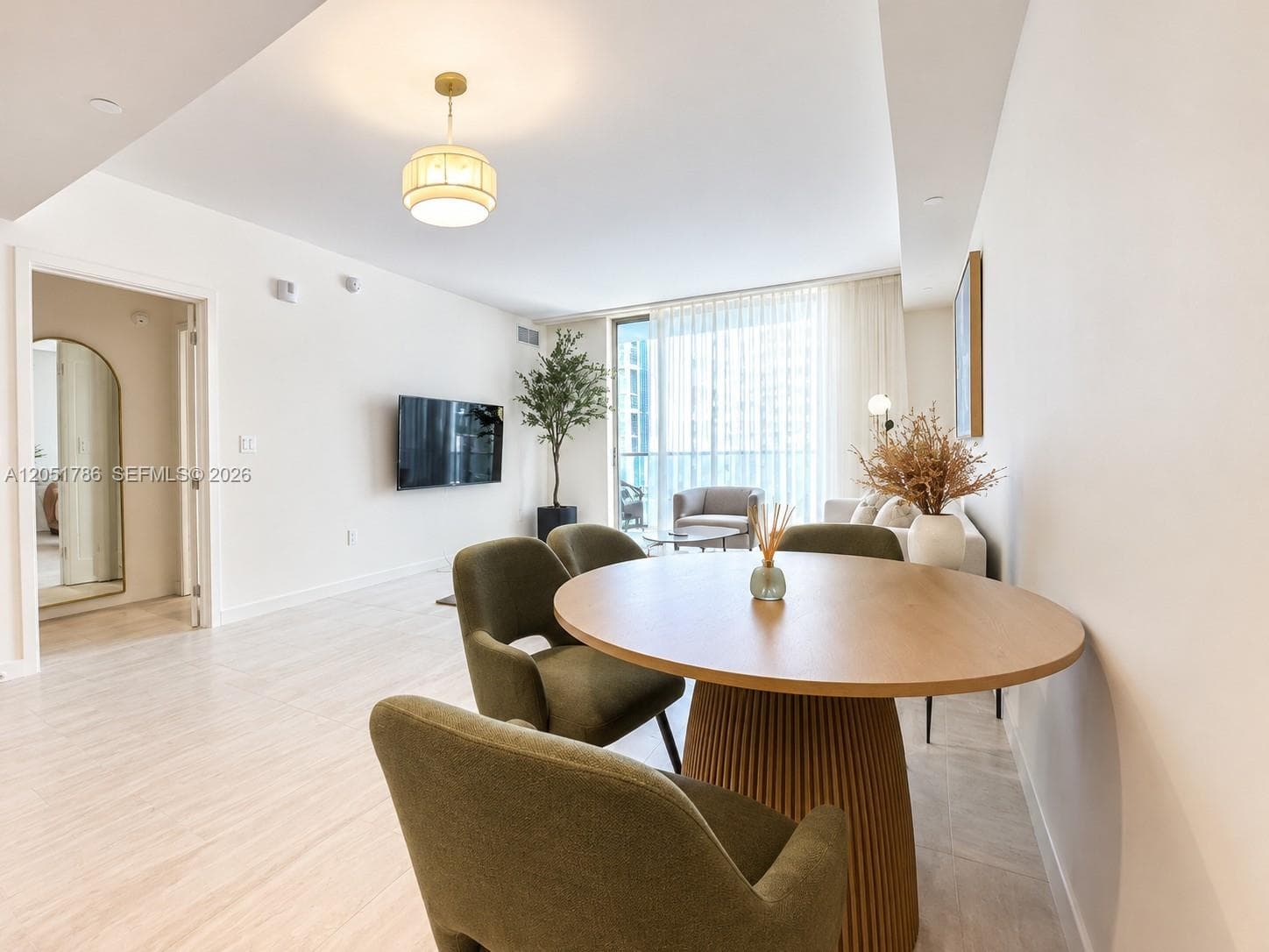 Open-concept interior featuring light wood-finish flooring, recessed lighting, a modern drum pendant fixture, and a floor-to-ceiling glass door