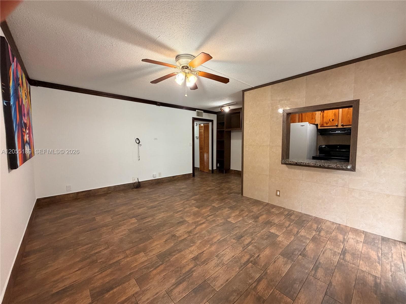Wood-finish flooring, ceiling fan with integrated lighting, tiled accent wall, and built-in shelving