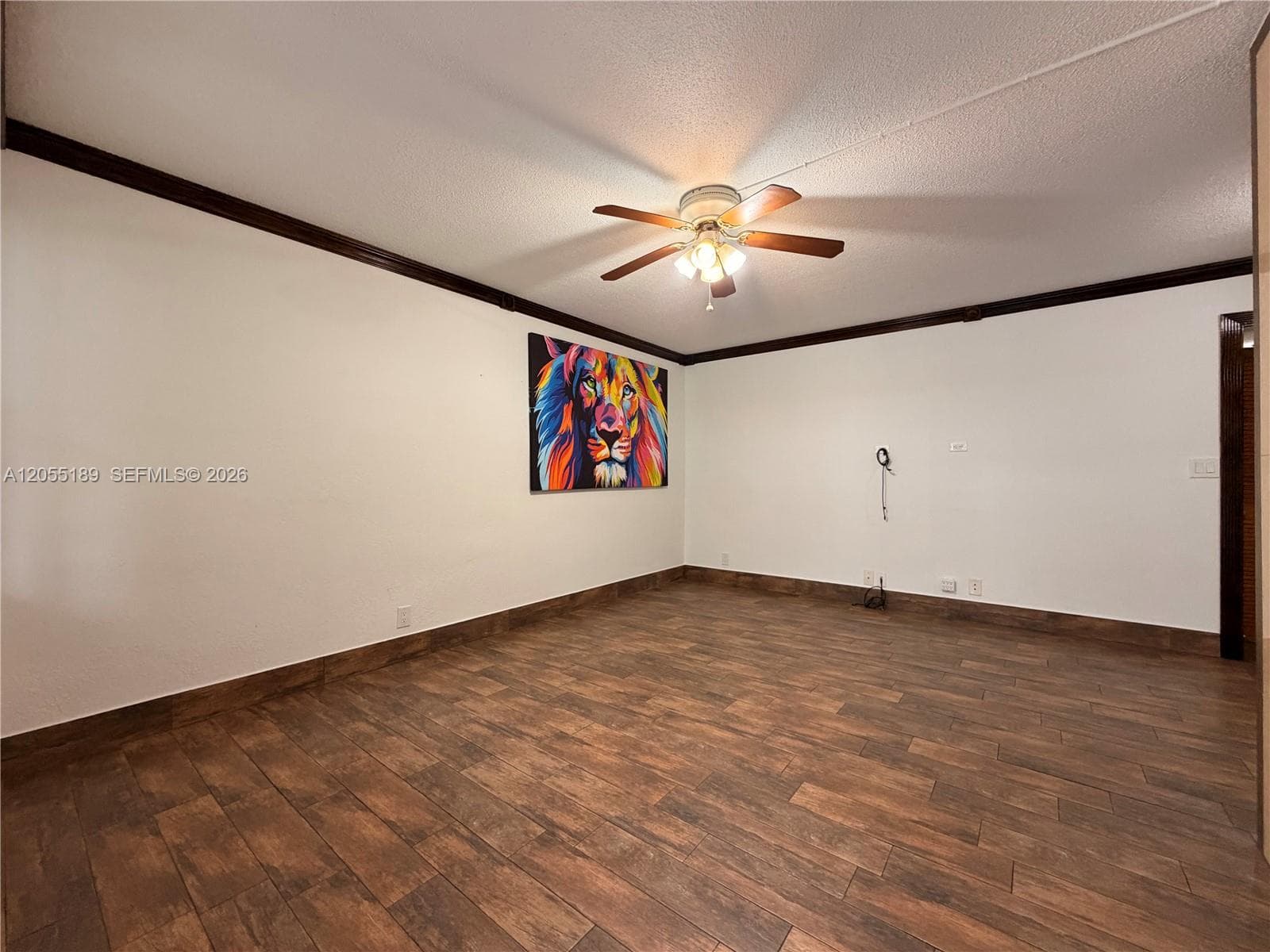 Wood-finish tile flooring, dark crown molding, and a central ceiling fan with integrated lighting