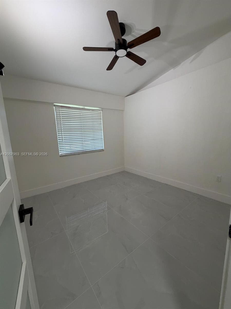 Light gray tile flooring with a subtle pattern, white walls, and a dark-toned ceiling fan