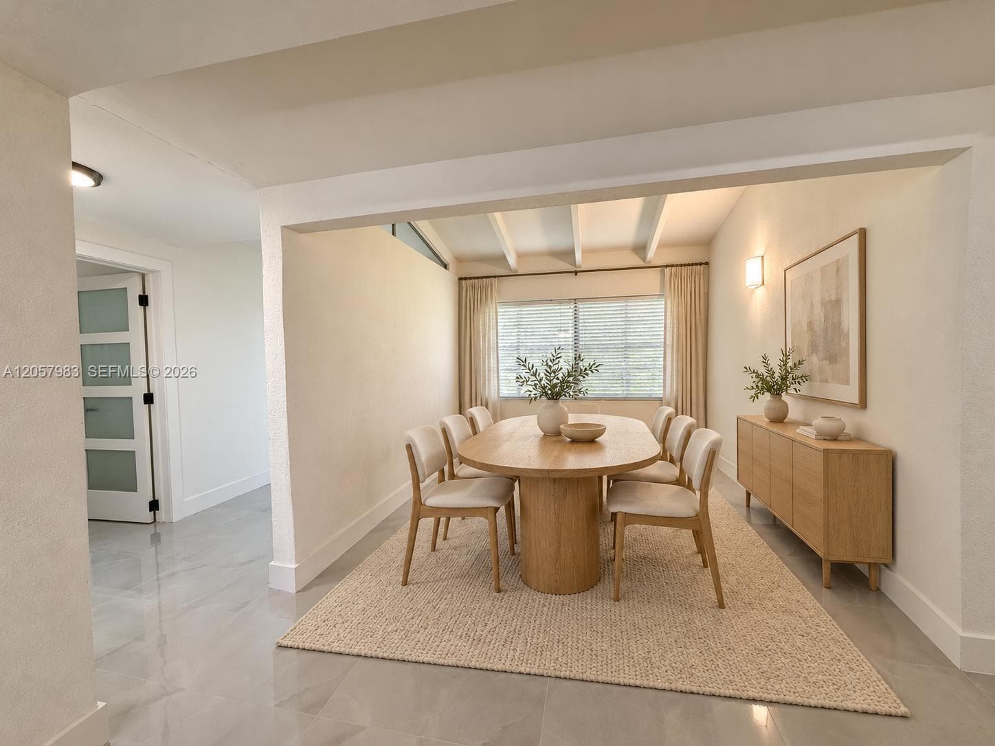 Recessed ceiling lighting, exposed ceiling beams, wall-mounted light fixture, light wood-finish flooring, and a window with blinds and curtains