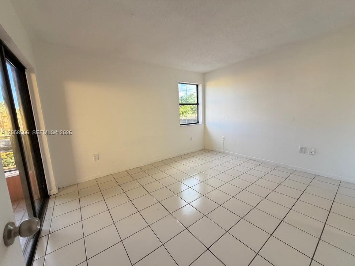 Interior space featuring white tile flooring, neutral walls, a single-pane window, and a sliding glass door