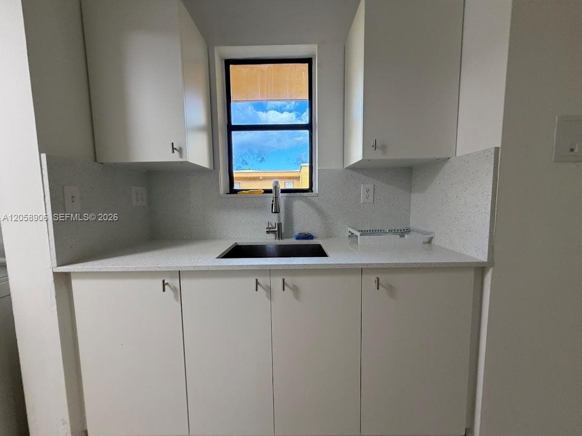 White cabinetry, solid surface countertop with integrated backsplash, undermount sink, and high-arc pull-down faucet