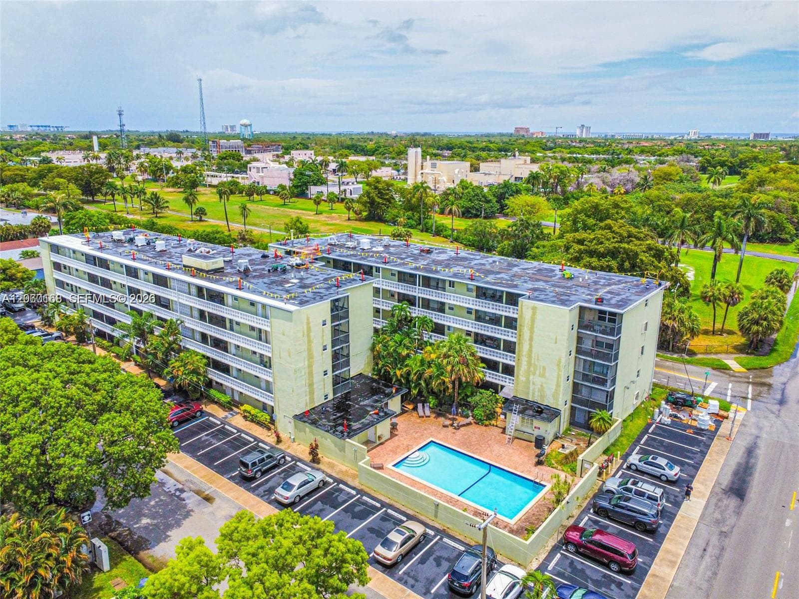 Multi-story residential building featuring a swimming pool, paved surface parking, and exterior balconies