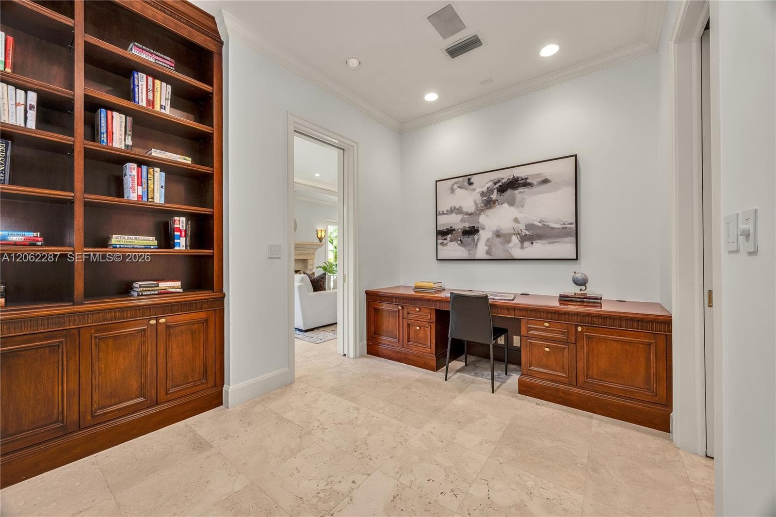 Custom wood-finish floor-to-ceiling cabinetry, integrated wooden built-in desk, stone tile flooring, and recessed ceiling lighting