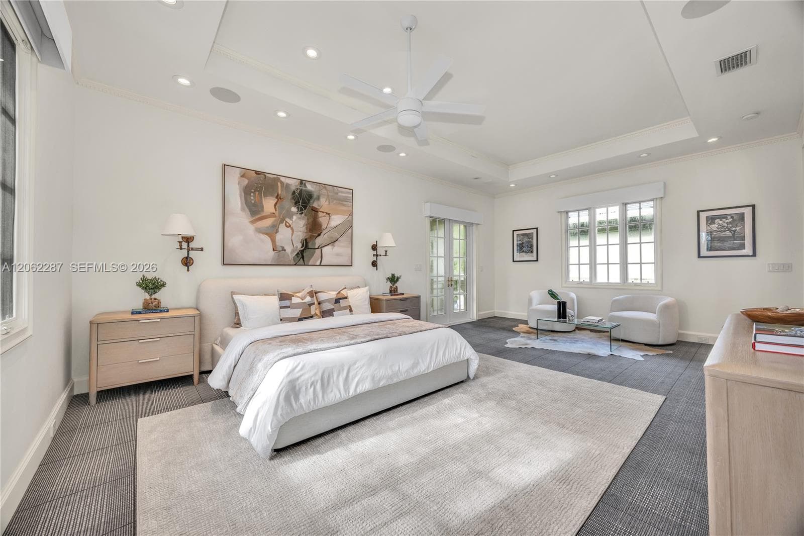 Spacious room featuring a recessed tray ceiling, white multi-blade ceiling fan, integrated recessed lighting, grid-pattern windows, and multi-light French doors