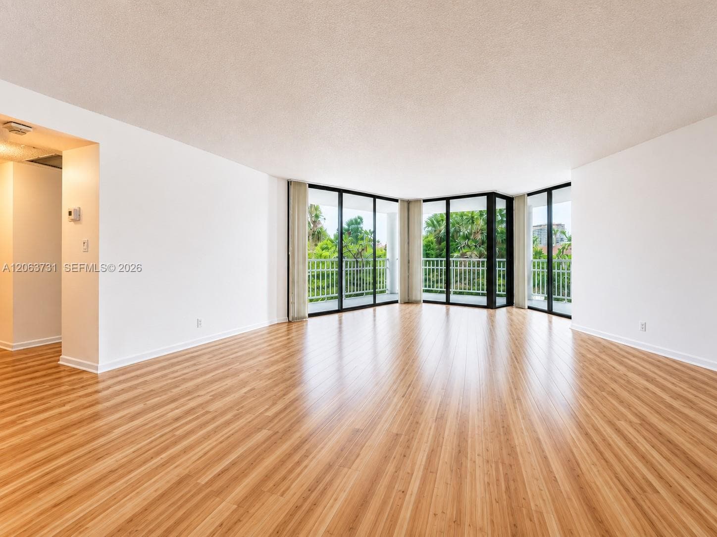 Open-concept interior featuring wood-finish flooring, floor-to-ceiling glass windows, and a wraparound balcony