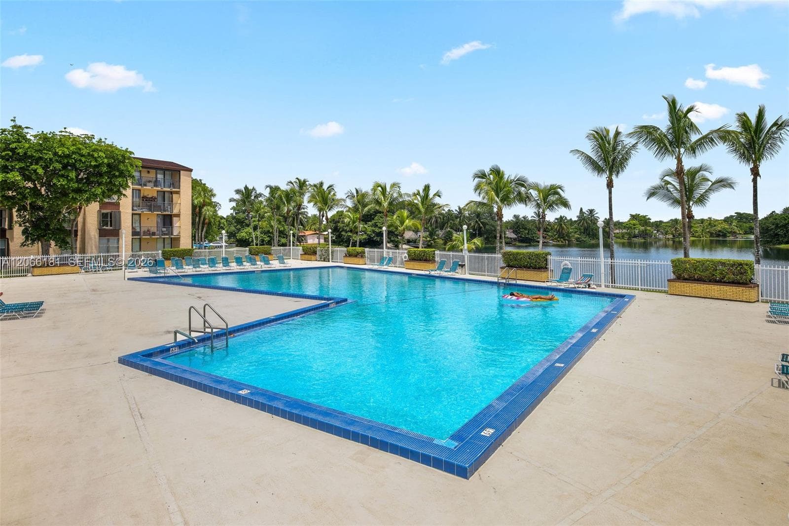 Primary swimming pool overlooking lake next to tennis courts