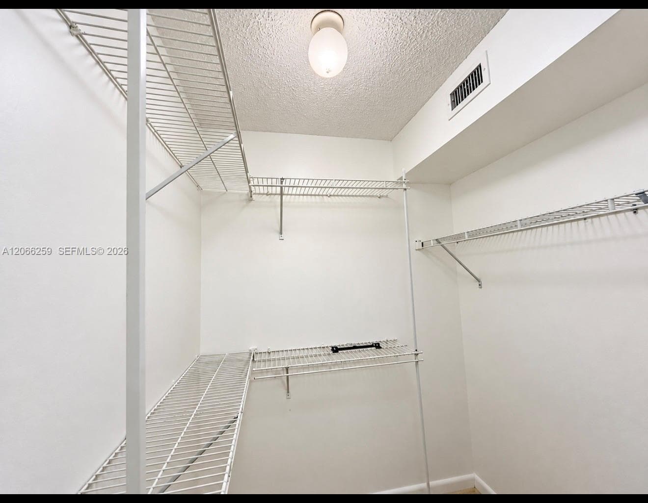 Storage area featuring tiered white wire shelving and a ceiling-mounted globe light fixture