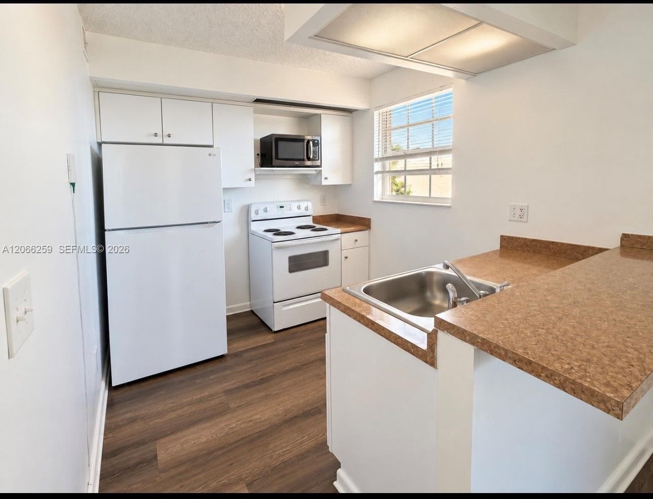 Kitchen featuring white cabinetry, wood-finish flooring, a stainless steel sink, and recessed lighting