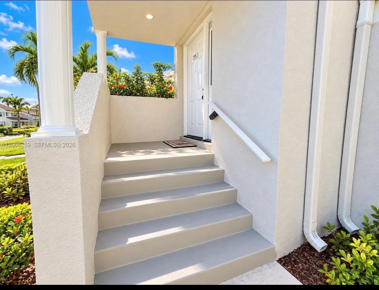 Covered entryway featuring a painted concrete staircase, classic column support, and a white paneled front door