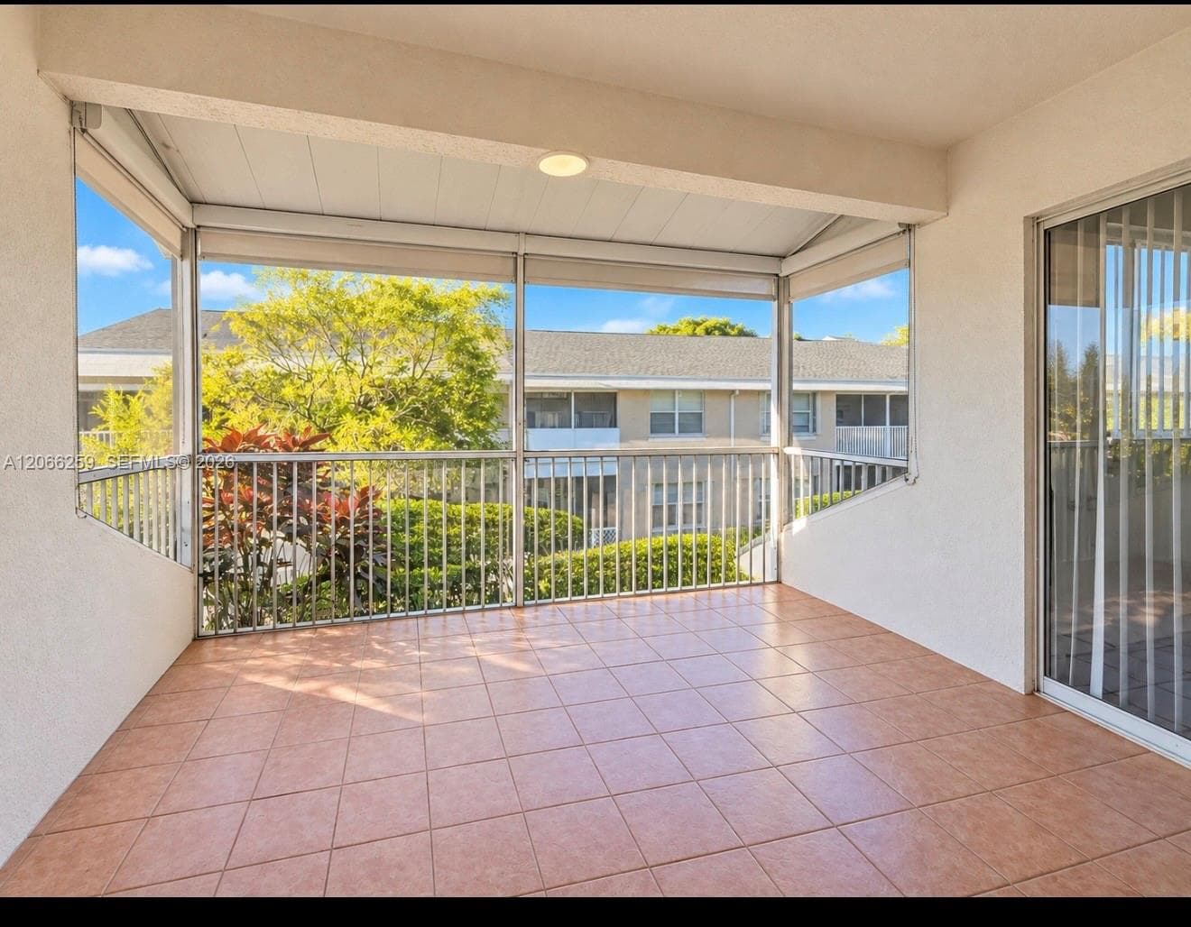 Screened-in balcony featuring tile flooring, a covered ceiling, and metal railings