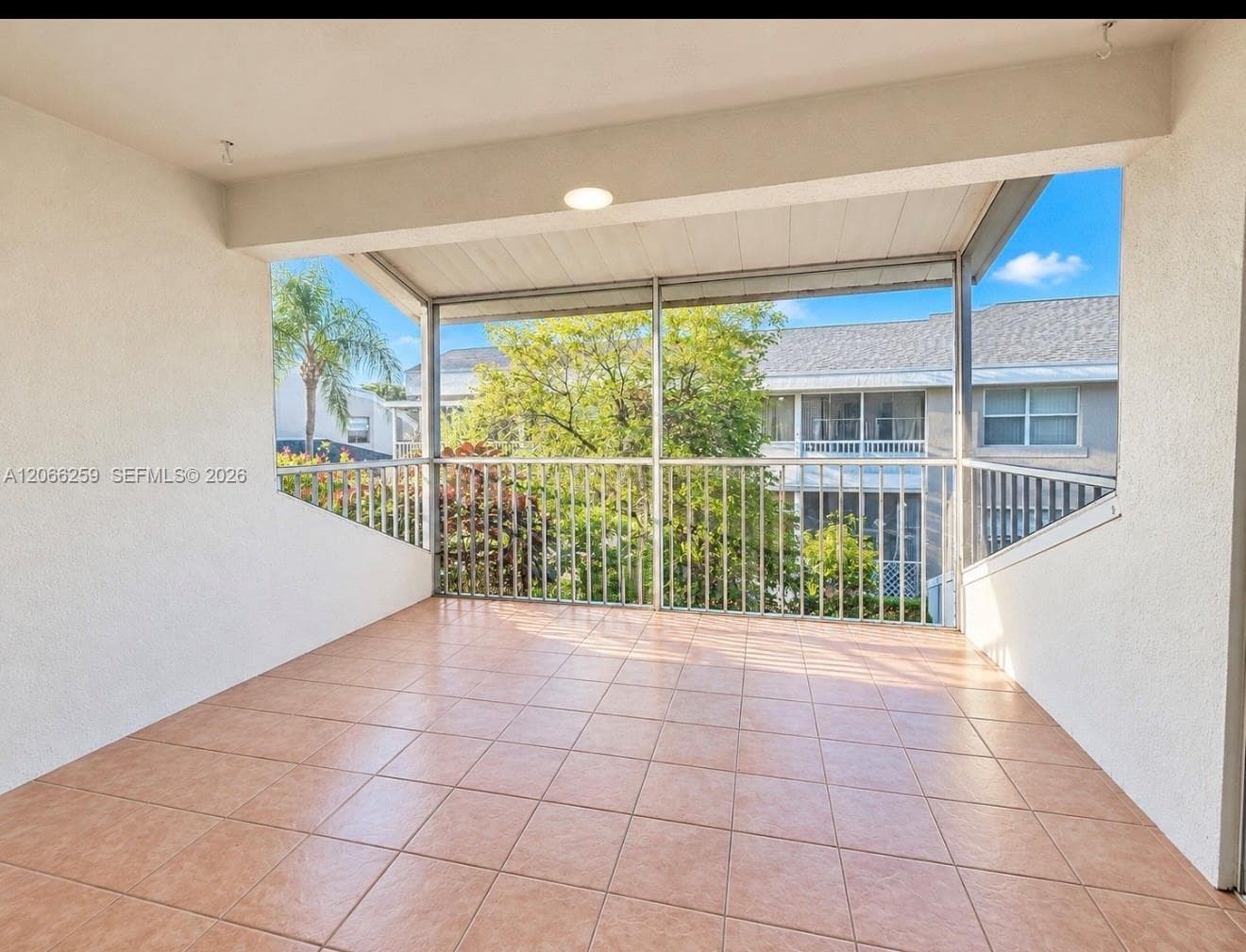 Covered balcony featuring tile flooring, a screen enclosure, and metal railings