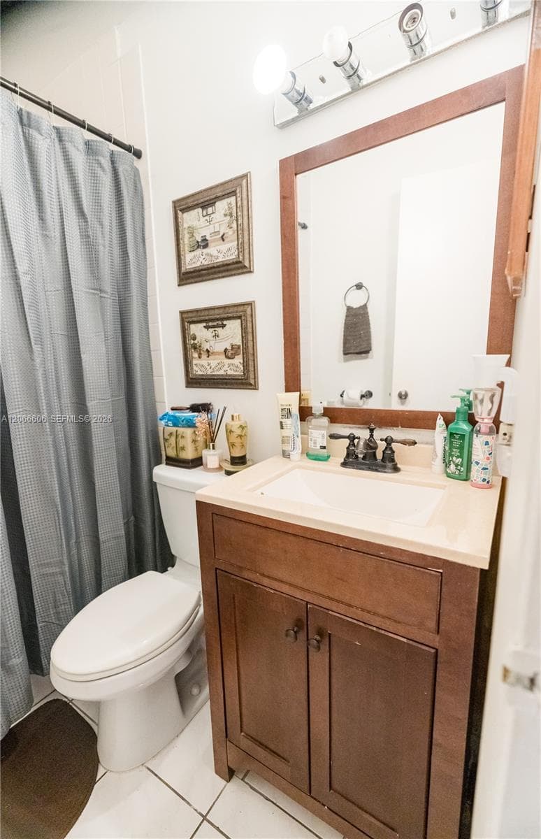 Bathroom featuring a wooden vanity with a light-toned countertop, rectangular undermount sink, multi-bulb vanity light fixture, and framed wood-trimmed mirror