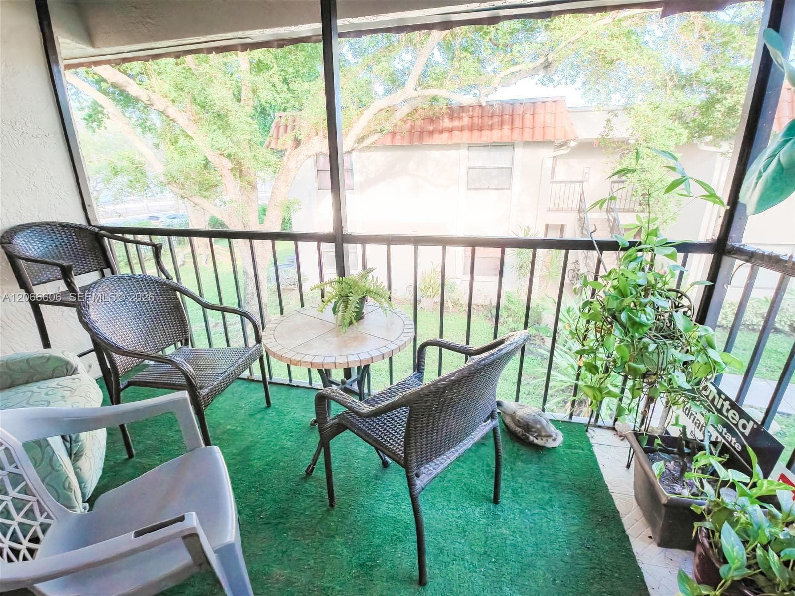 Screened-in balcony featuring black metal railings and overhead framing