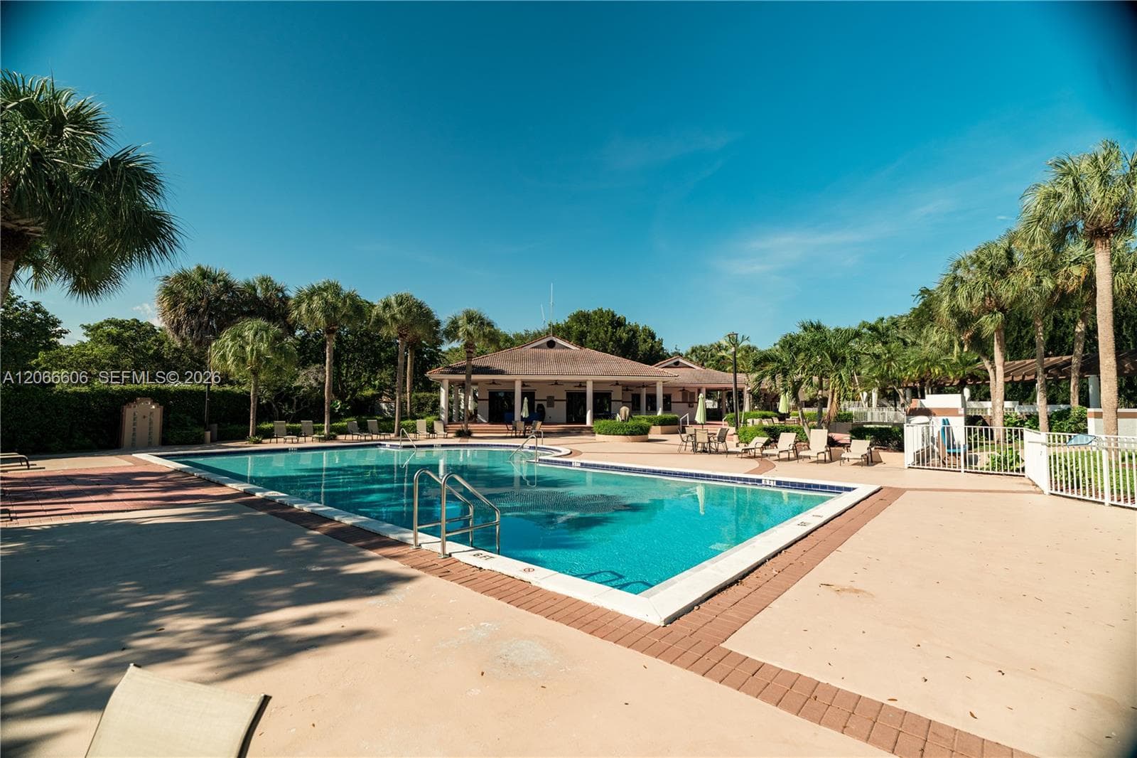 Swimming pool, covered clubhouse structure surrounded by palm trees