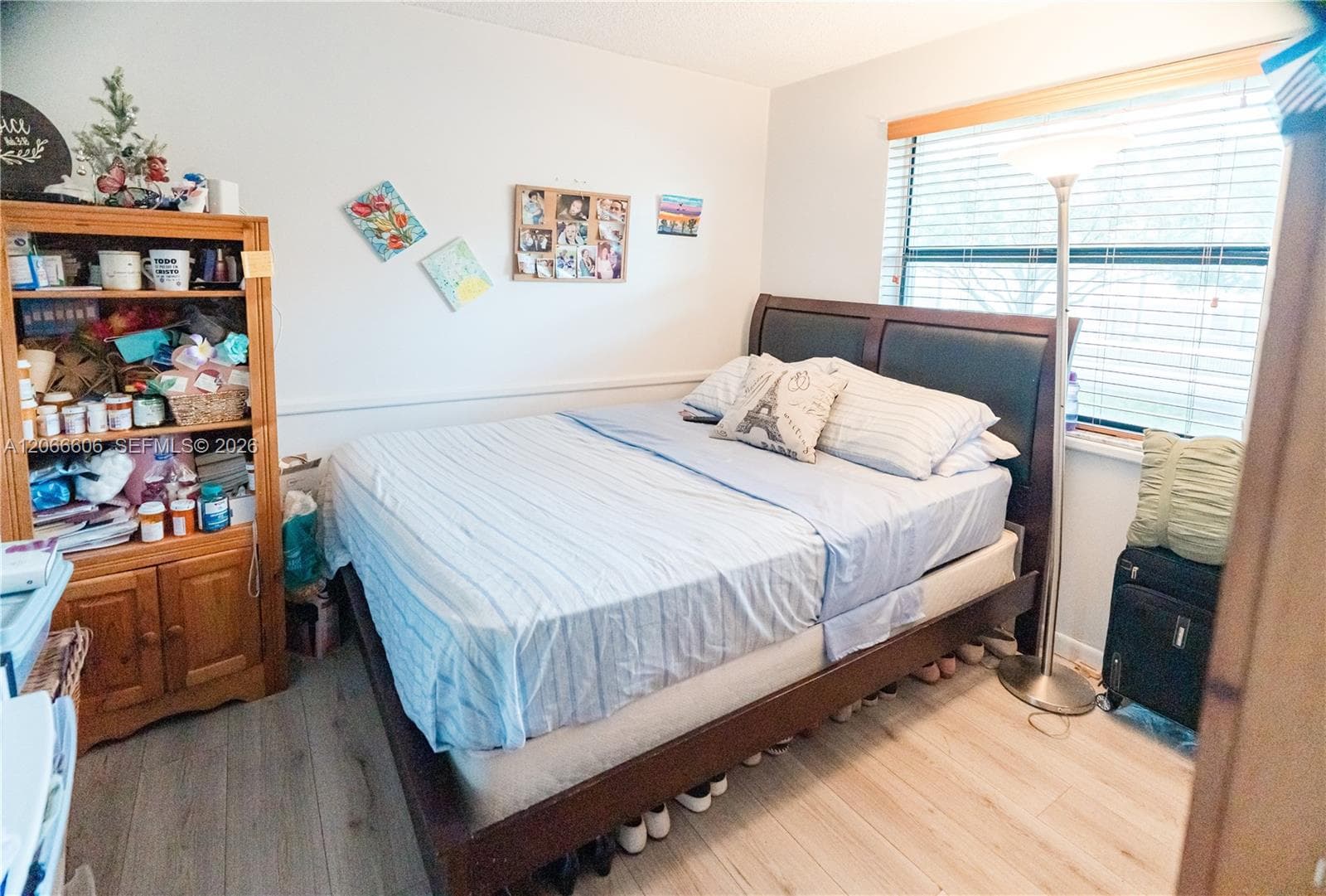 Room featuring light-toned wood-finish flooring, a large window with horizontal blinds, and a chair rail