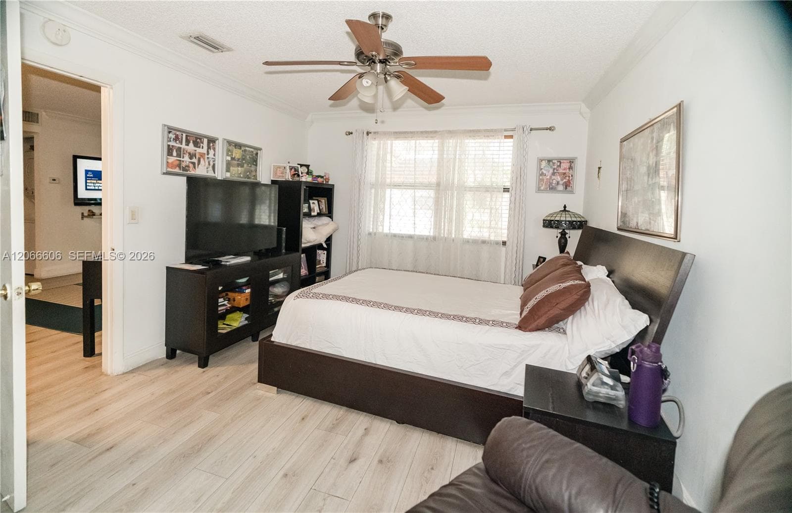 Room featuring wood-finish flooring, a multi-blade ceiling fan with integrated lighting, crown molding, and dual-pane windows with horizontal blinds