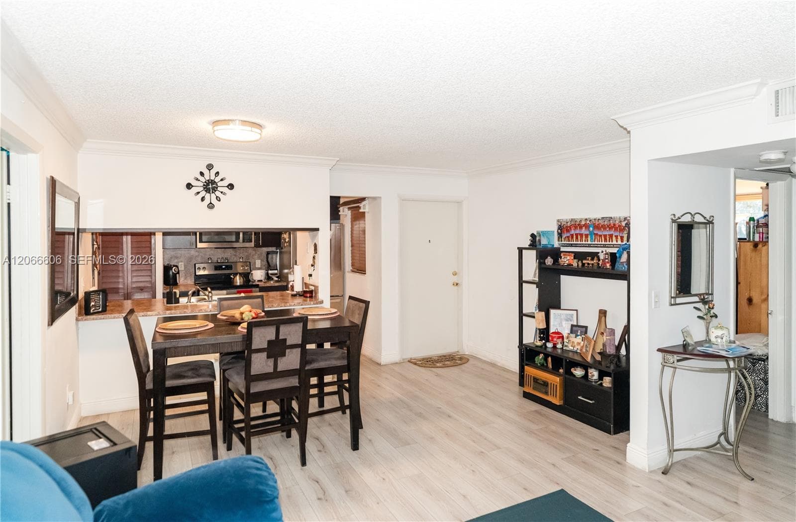 Open-concept floor plan featuring wood-finish flooring, crown molding, and a kitchen pass-through breakfast bar