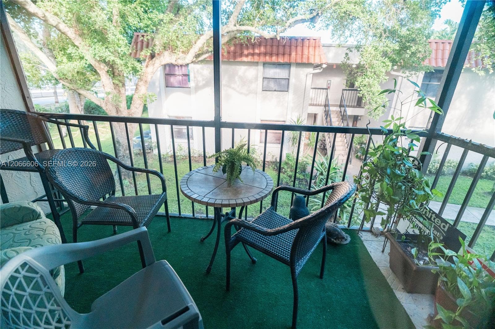 Screened balcony featuring metal railing, outdoor carpeting, and concrete flooring
