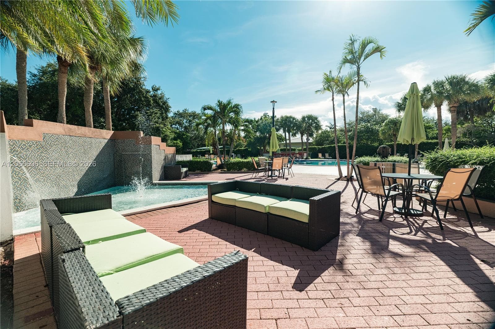 Outdoor recreation area a built-in water feature with stone-tile surround, and mature palm trees