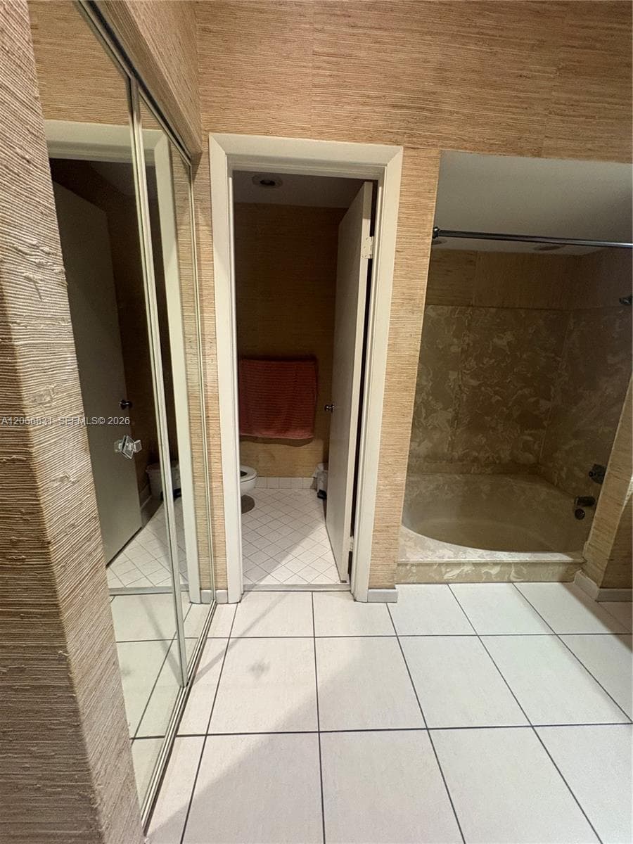 Textured wall finishes, large-format tile flooring, mirrored sliding closet doors, and a built-in soaking tub with surround tile