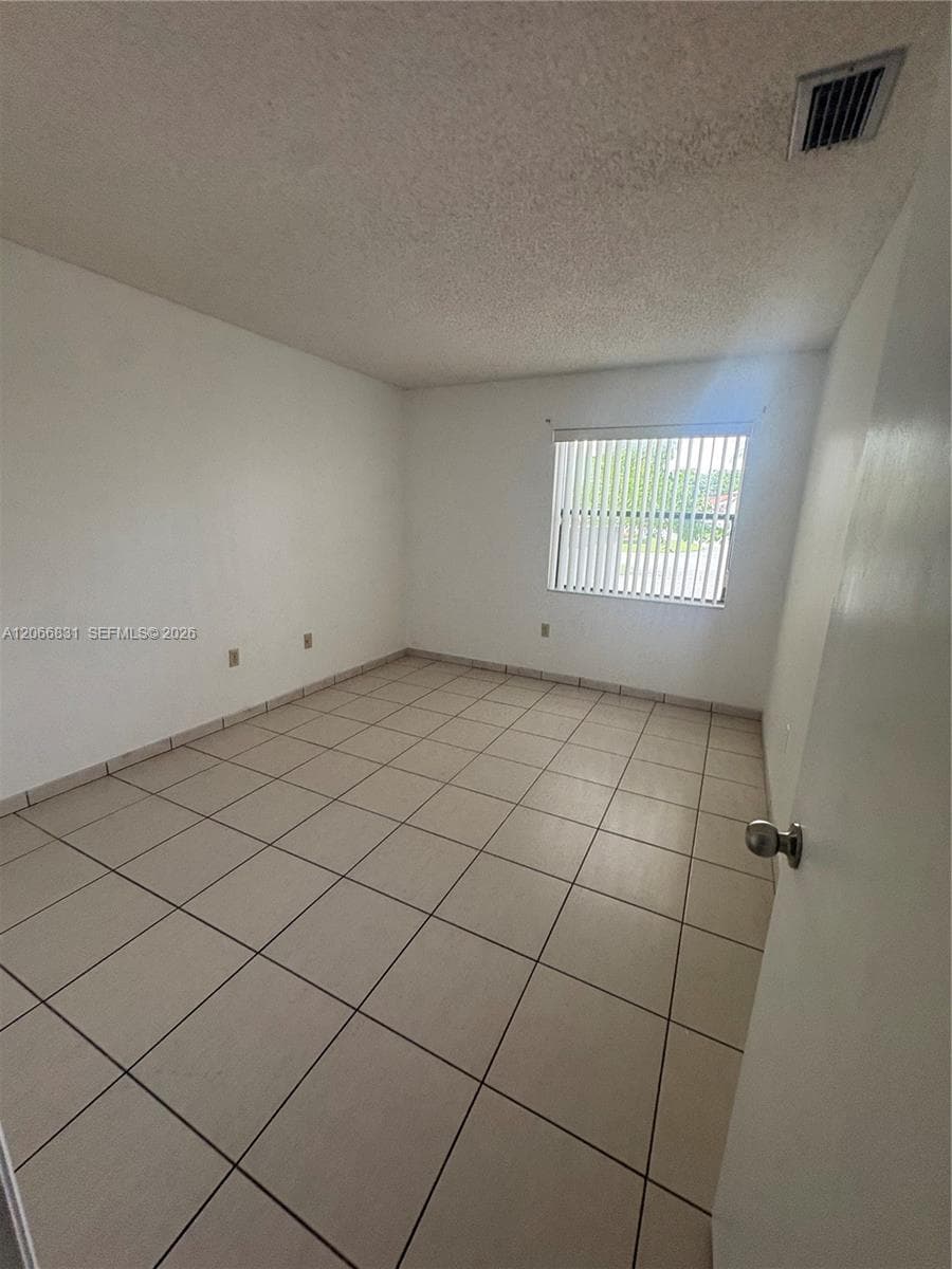 Interior room featuring neutral ceramic tile flooring and a window with vertical blinds