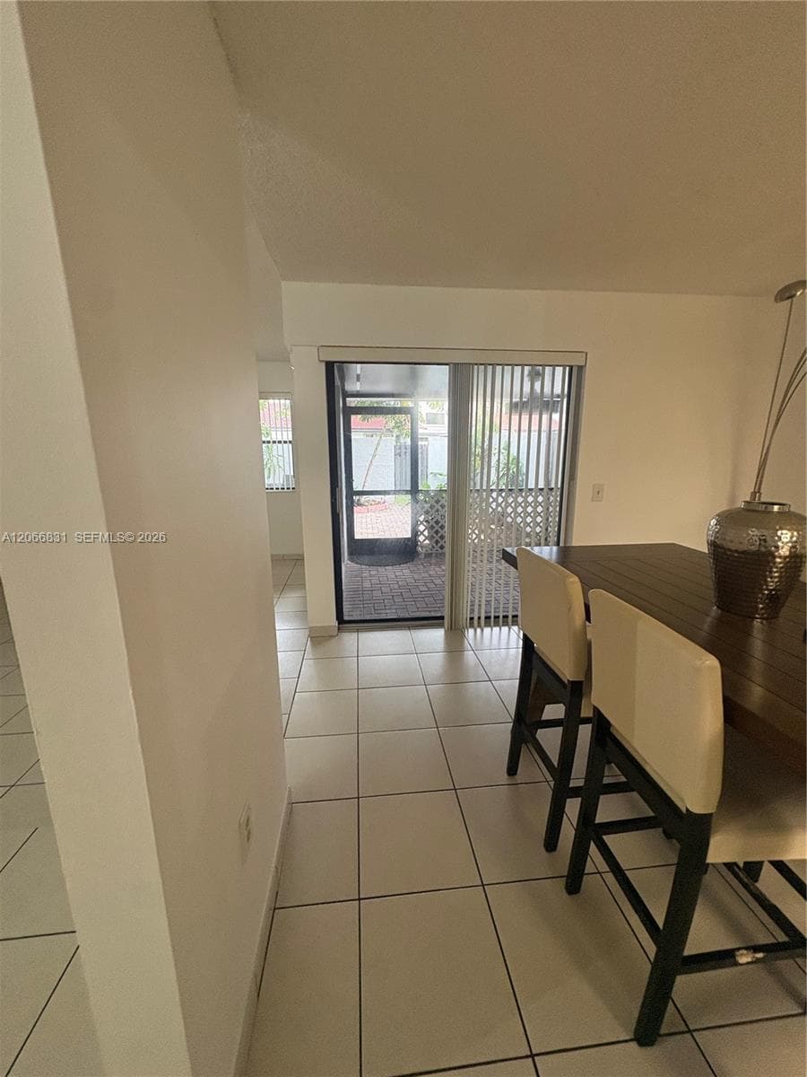 Ceramic tile flooring, sliding glass patio door, and enclosed outdoor space with brick pavers