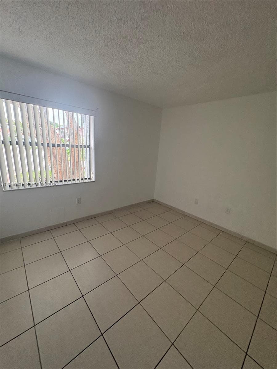 Room featuring ceramic tile flooring, neutral wall tones, and a window with vertical blinds