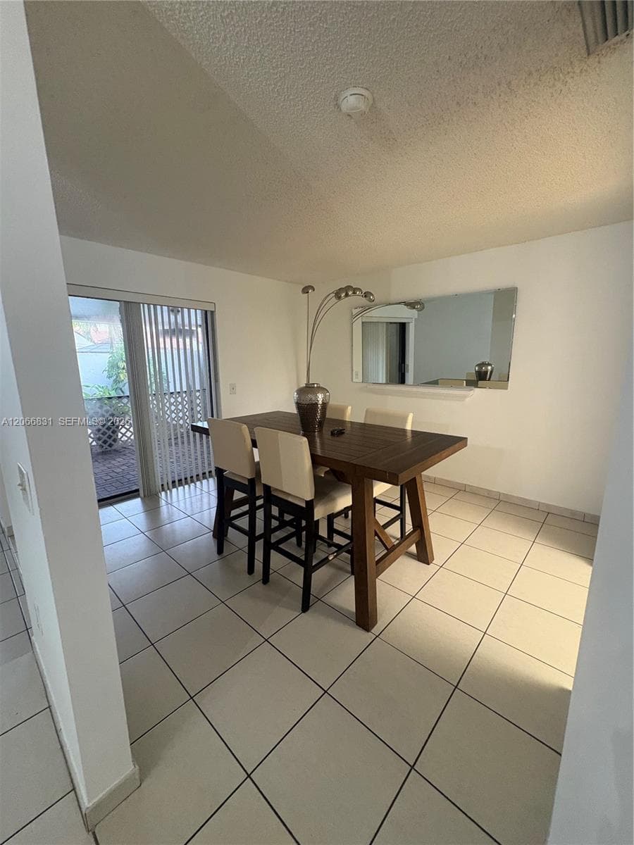 Neutral-toned ceramic tile flooring, built-in wall mirror, and sliding glass door with vertical blinds