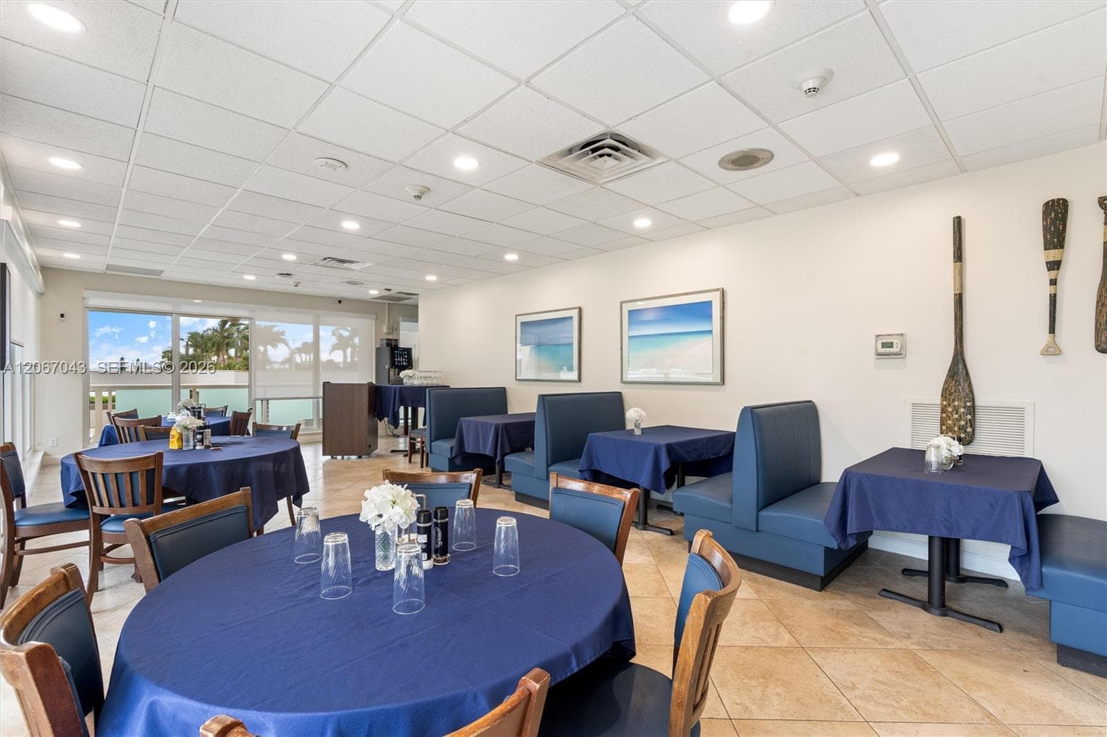 Spacious room featuring a drop ceiling with recessed lighting, large-format tile flooring, and floor-to-ceiling glass windows