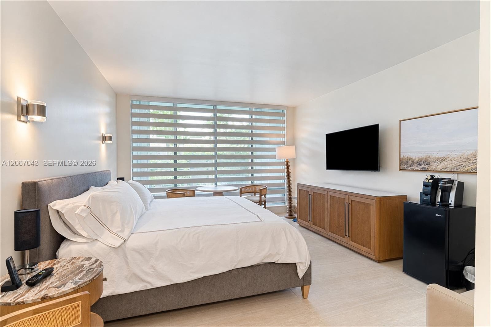 Expansive window wall with adjustable shades, tile flooring, and wall-mounted light fixtures