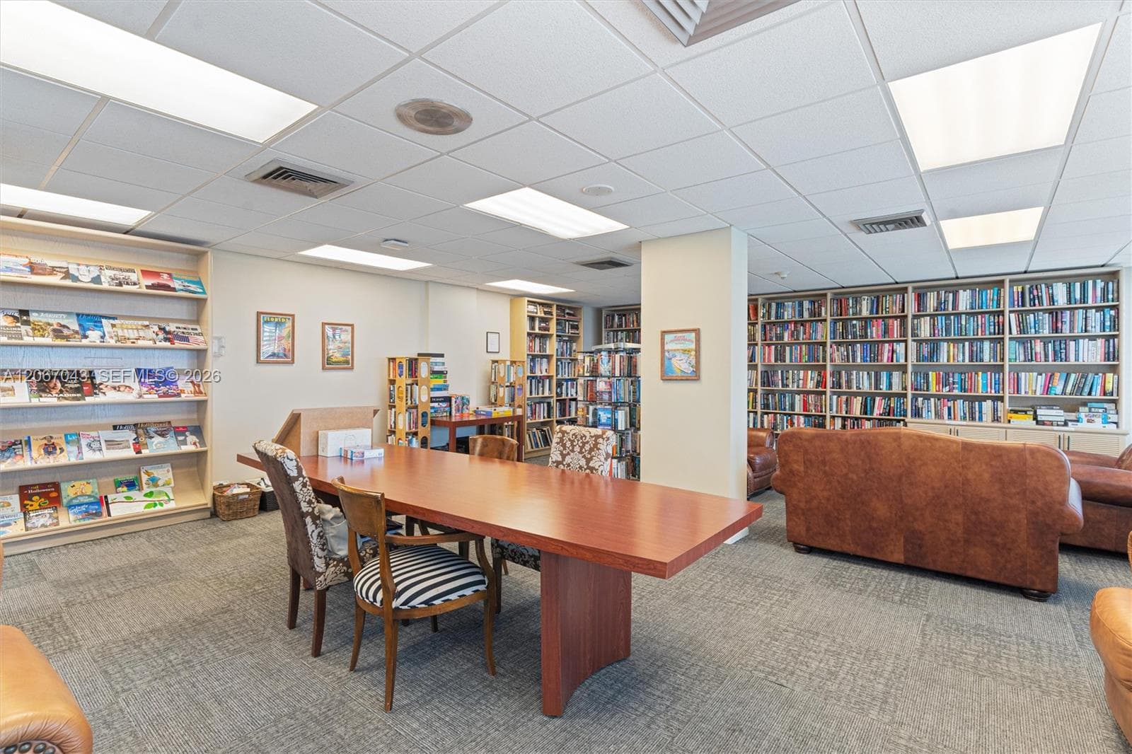 Spacious room featuring floor-to-ceiling built-in wooden shelving, recessed and panel lighting, and wall-to-wall carpeting