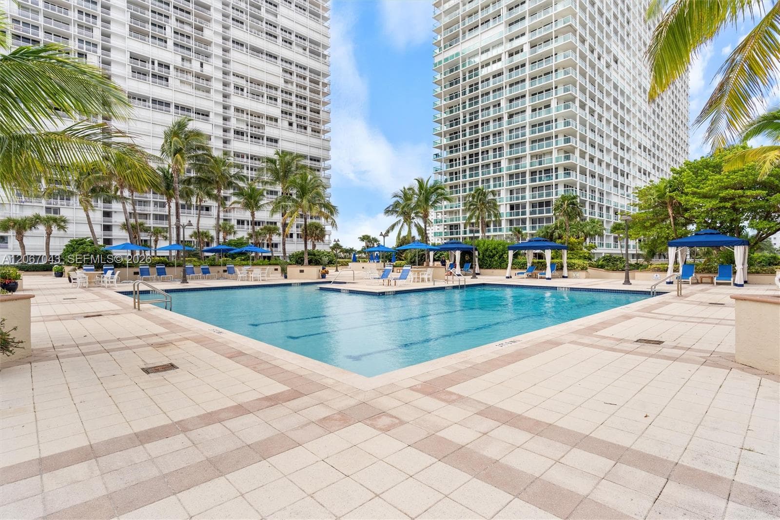 Swimming pool with a tile deck, shaded cabanas, and integrated landscaping