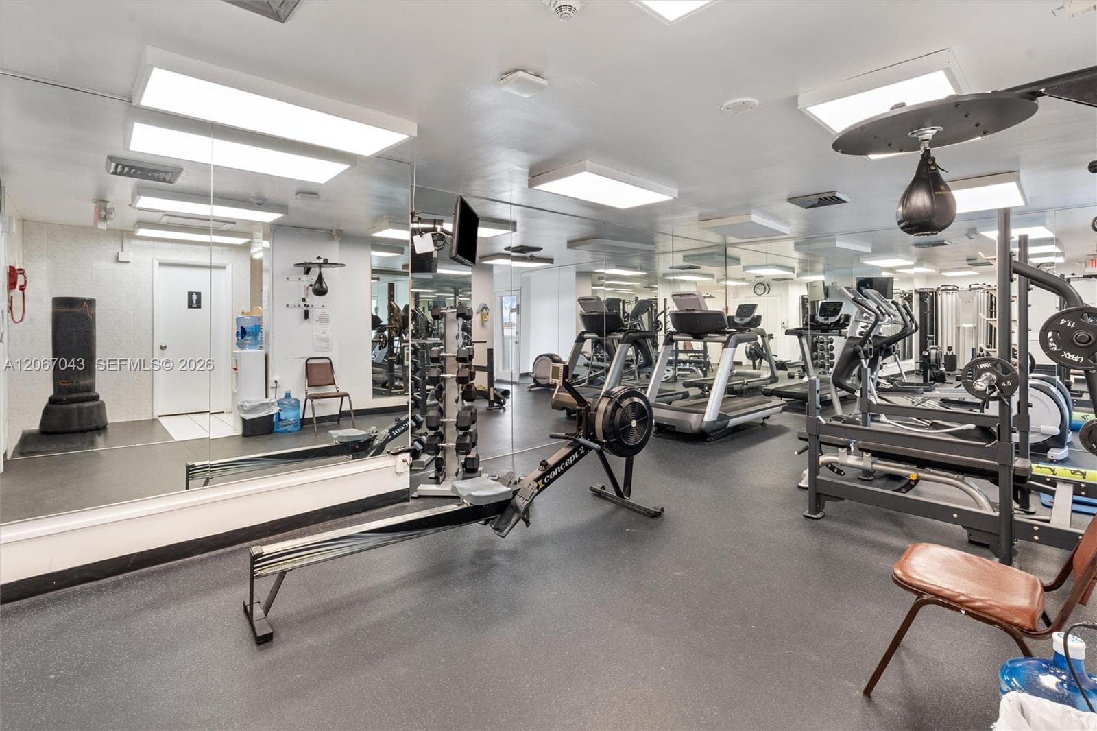Fitness facility featuring full-wall mirrors, durable rubberized flooring, and recessed ceiling lighting