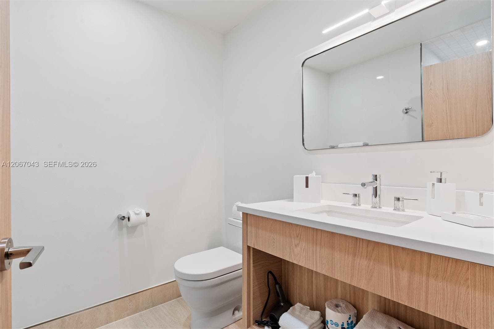 Wood-finish vanity with an integrated rectangular sink and solid-surface countertop, rounded-corner mirror, and chrome faucet hardware