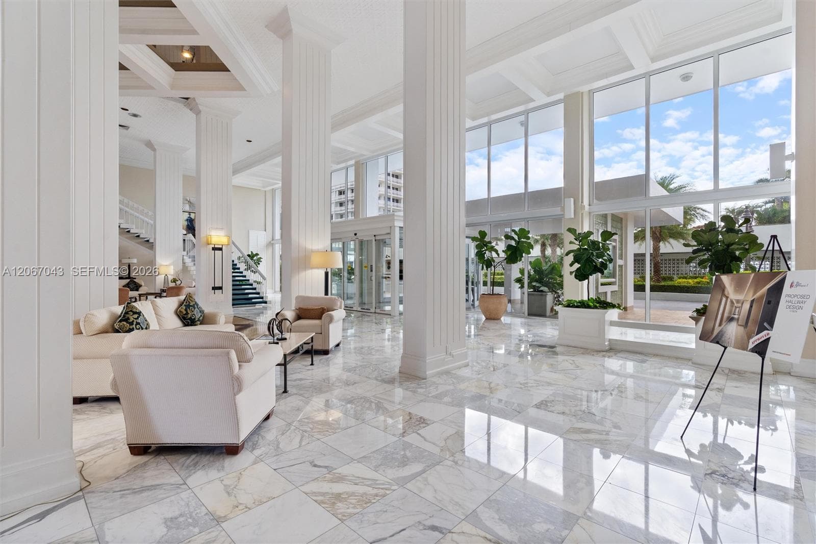 Grand lobby featuring expansive floor-to-ceiling windows, polished stone tile flooring, structural columns with fluted detailing, and coffered ceilings