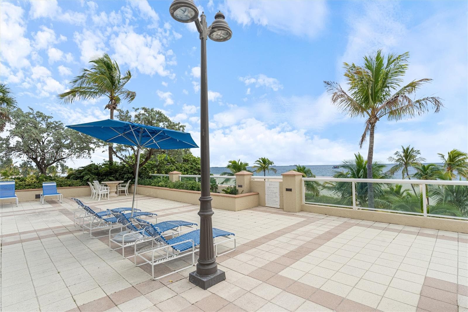 Expansive tiled terrace featuring a structural glass railing and a decorative metal light post