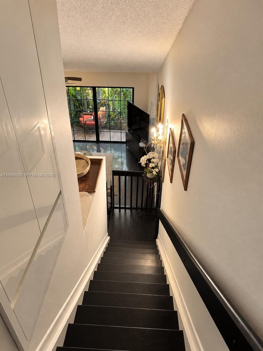 Staircase featuring dark-stained wood treads, matte black handrail, and large-format glass paneled doors providing exterior visibility