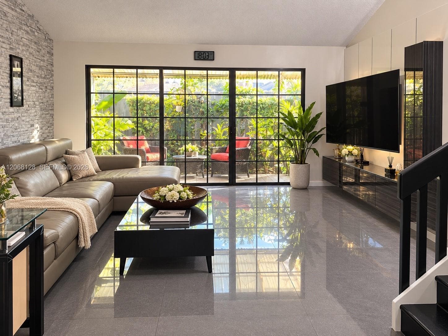 Living area featuring large-format tile flooring, a floor-to-ceiling stone-veneer accent wall, floor-to-ceiling black-framed glass sliding doors, and custom built-in dark cabinetry