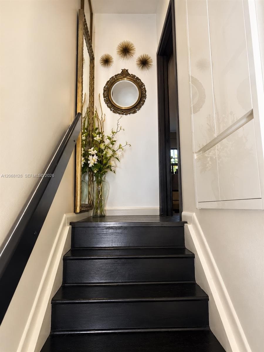 Staircase featuring dark-finished wooden treads and a matching handrail, paired with white paneling and trim
