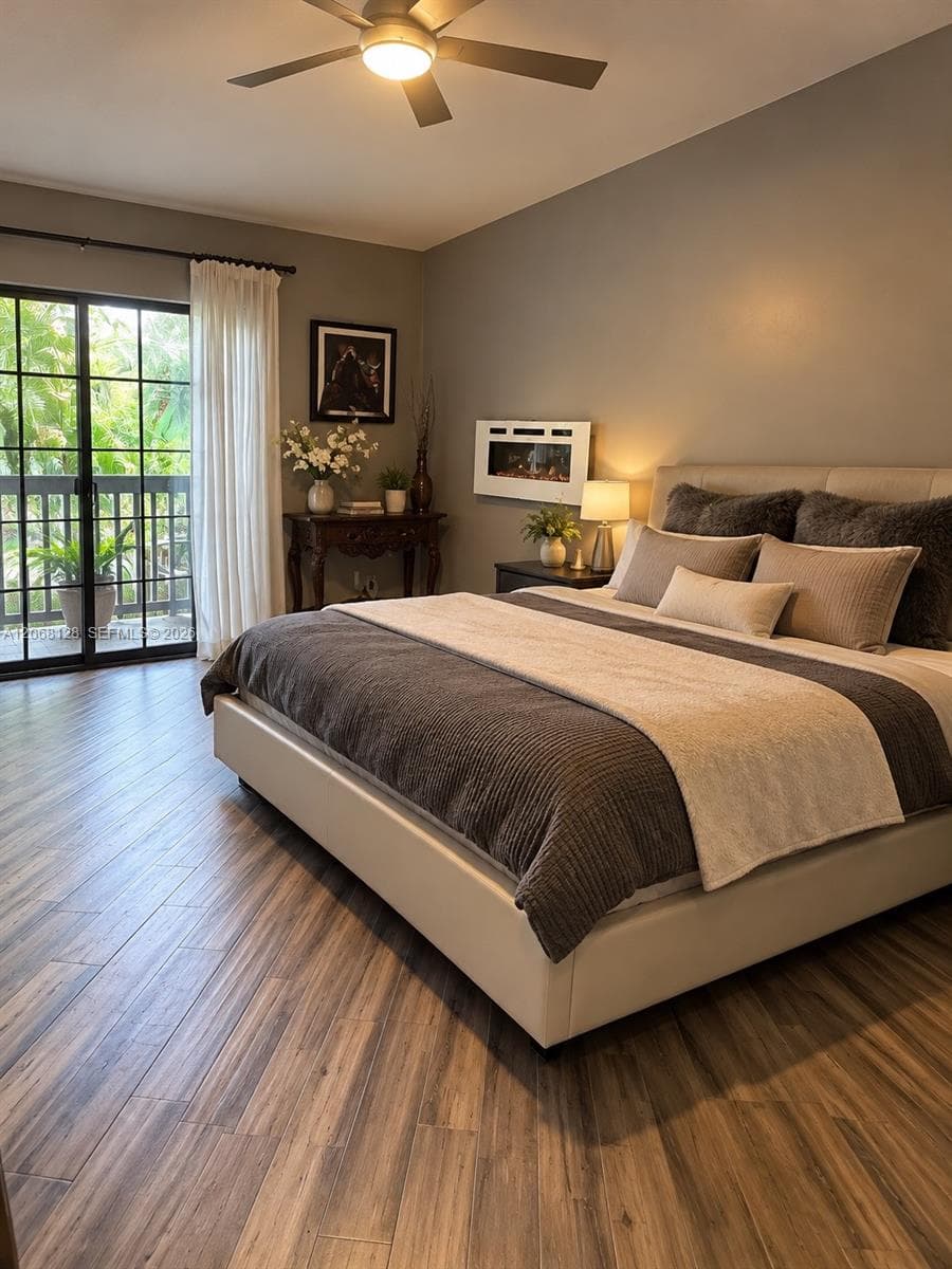 Wood-finish flooring, wall-mounted electric fireplace, ceiling fan with integrated lighting, and black-framed sliding glass doors opening to a balcony