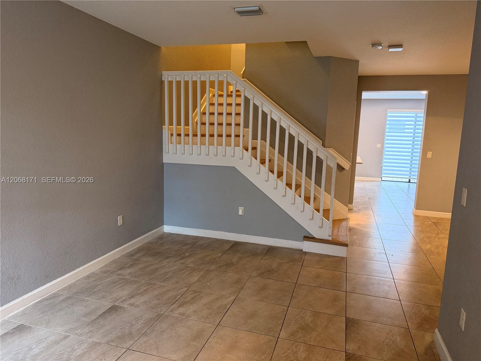 Staircase with white balusters and wood-finish treads, complemented by neutral tile flooring throughout