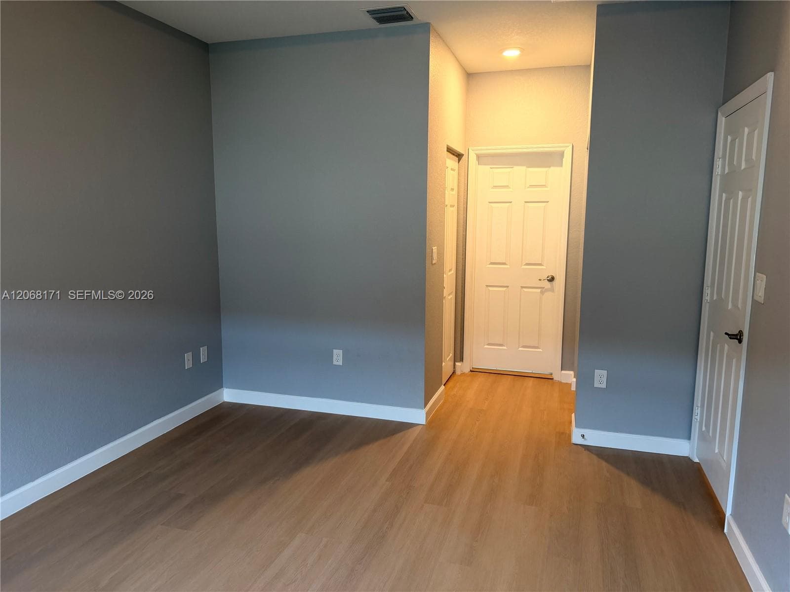 Neutral-toned interior featuring wood-finish flooring, recessed lighting, and two white panel doors