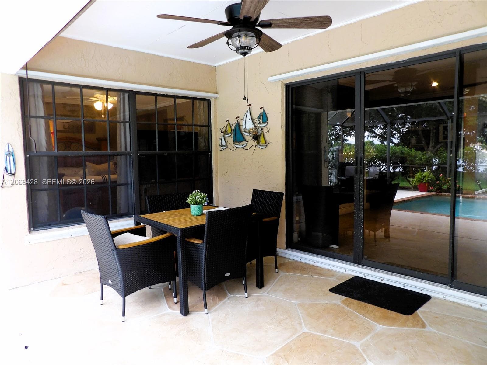 Covered patio with a patterned concrete floor, ceiling fan, and large sliding glass doors