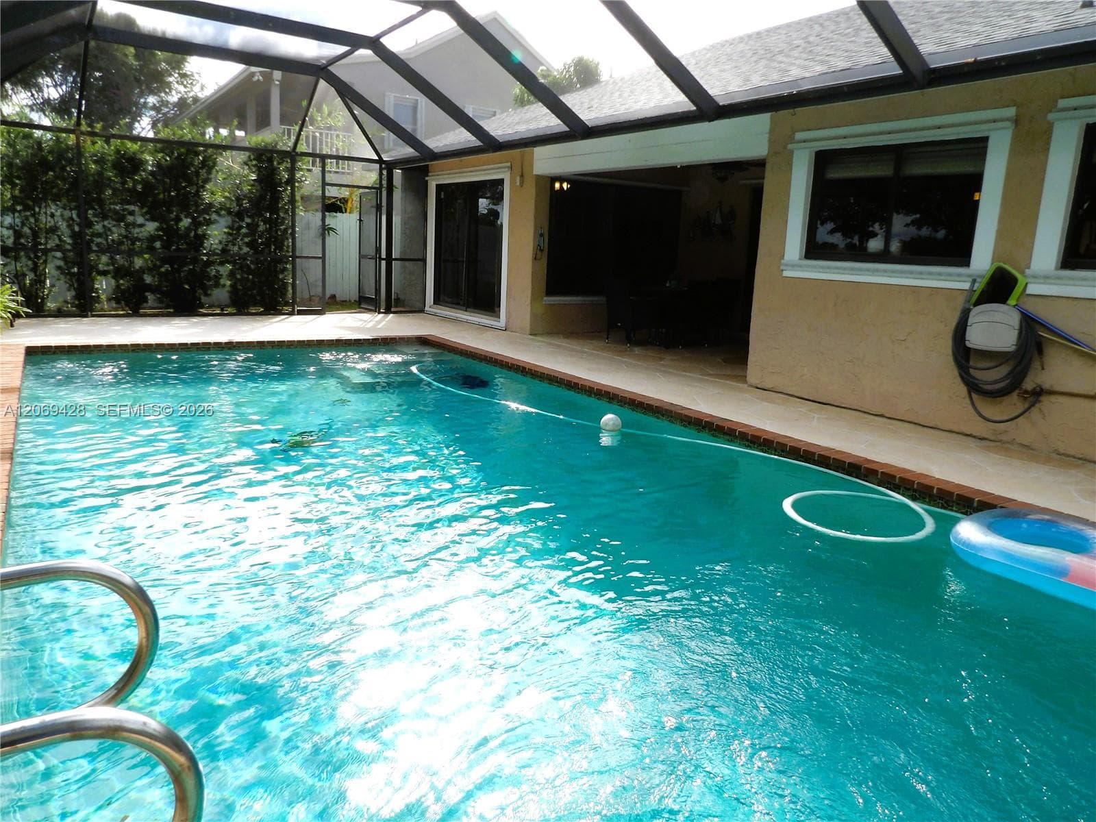 Screened outdoor swimming pool with surrounding concrete patio and stucco exterior