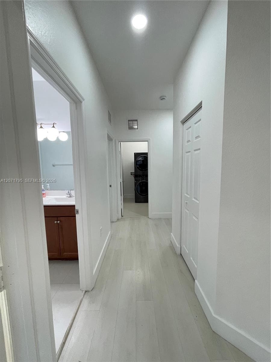 Hallway featuring light-toned wood-finish flooring, recessed lighting, and white six-panel closet doors