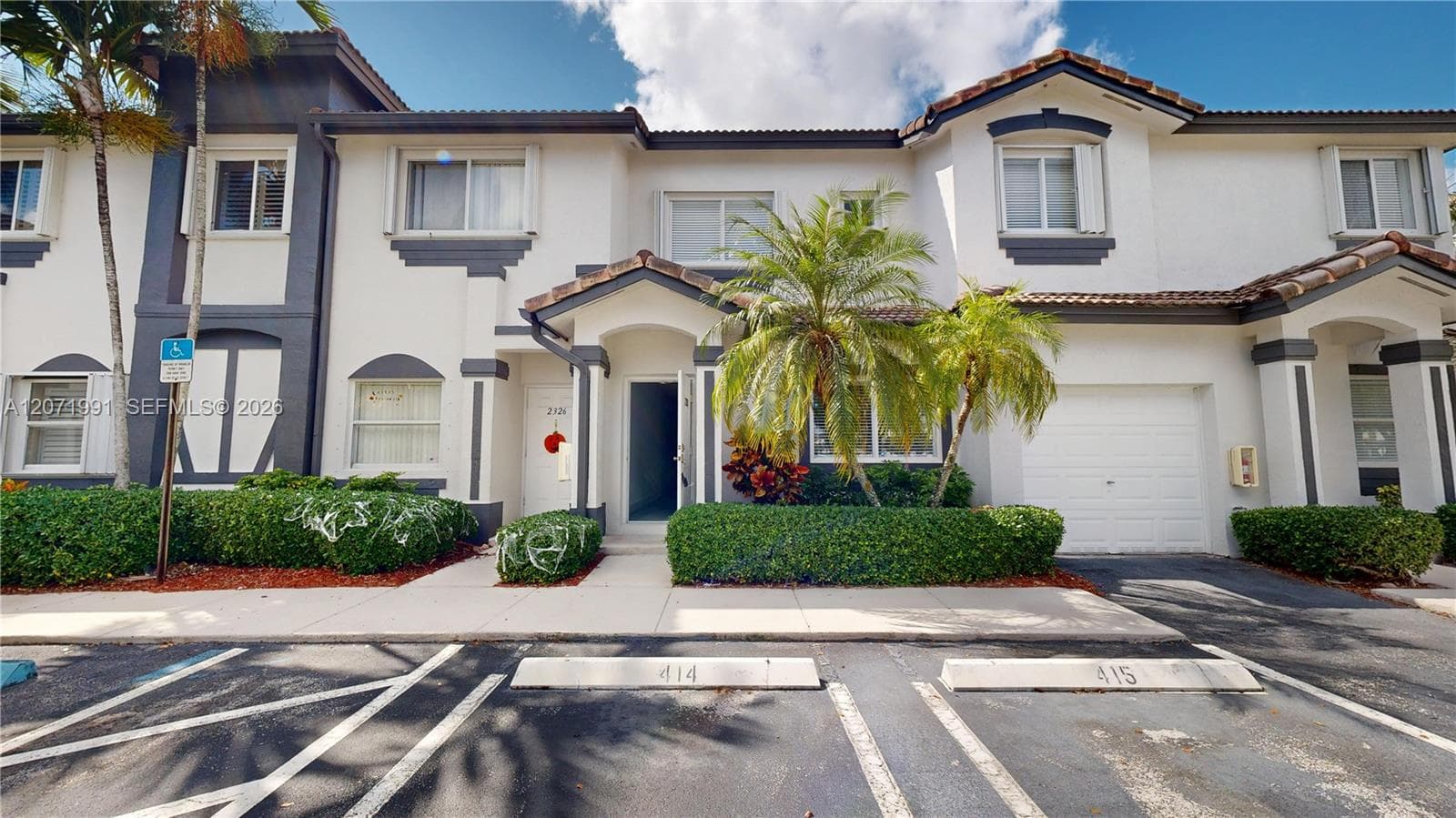 Stucco exterior featuring dual-tone trim, a tiled roof, an integrated single-car garage, and manicured landscaping